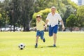 Young happy father and excited little 7 or 8 years old son playing together soccer football on city park garden running on grass k Royalty Free Stock Photo