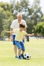 Young happy father and excited little 7 or 8 years old son playing together soccer football on city park garden running on grass k Royalty Free Stock Photo