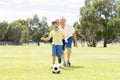 Young happy father and excited little 7 or 8 years old son playing together soccer football on city park garden running on grass k Royalty Free Stock Photo