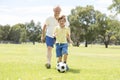 Young happy father and excited little 7 or 8 years old son playing together soccer football on city park garden running on grass k Royalty Free Stock Photo