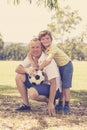 Young happy father and excited 7 or 8 years old son playing together soccer football on city park garden posing sweet and loving h Royalty Free Stock Photo