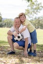 Young happy father and excited 7 or 8 years old son playing together soccer football on city park garden posing sweet and loving h Royalty Free Stock Photo