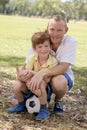 Young happy father and excited 7 or 8 years old son playing together soccer football on city park garden posing sweet and loving h Royalty Free Stock Photo