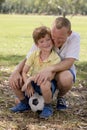 Young happy father and excited 7 or 8 years old son playing together soccer football on city park garden posing sweet and loving h Royalty Free Stock Photo