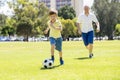 Young happy father and excited little 7 or 8 years old son playing together soccer football on city park garden running on grass k Royalty Free Stock Photo