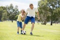 Young happy father and excited little 7 or 8 years old son playing together soccer football on city park garden running on grass k Royalty Free Stock Photo