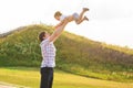 Young happy father holding baby son in hands over his head outdoors Royalty Free Stock Photo