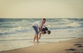 Young happy father holding in his arms little son playing on beach sand in front of sea waves Royalty Free Stock Photo