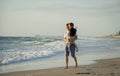 Young happy father holding in his arms little son walking on beach sand in front of sea waves Royalty Free Stock Photo