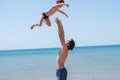 Young happy father holding up in his arms little son putting him up at the beach. Royalty Free Stock Photo