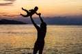 Young happy father holding up in his arms little son putting him up at the beach in barefoot standing in front of sea waves wet sa Royalty Free Stock Photo