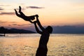 Young happy father holding up in his arms little son putting him up at the beach in barefoot standing in front of sea waves wet sa Royalty Free Stock Photo