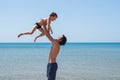 Young happy father holding up in his arms little son putting him up at the beach. Royalty Free Stock Photo