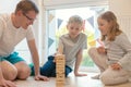 Young happy father playing with his two cute children with wooden blocks