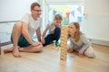 Young happy father playing with his two cute children with wooden blocks