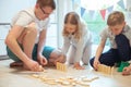 Young happy father playing with his two cute children with wooden blocks