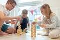 Young happy father playing with his two cute children with wooden blocks