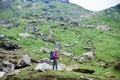 Young female climber standing on rock near tent on green rocky slope in mountains Royalty Free Stock Photo