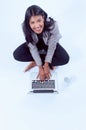 Young happy female sitting on the floor in front of the laptop