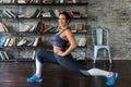 Young fitness woman doing leg stretching and smiling at home