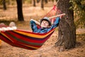 Young happy free man in hat relaxing outside in hammock in forest Royalty Free Stock Photo