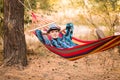 Young happy free man in hat relaxing outside in hammock in forest Royalty Free Stock Photo