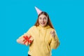 Young smiling happy fun woman point index finger on camera isolated on blue background, studio portrait. Female holding Royalty Free Stock Photo