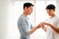 Young happy gay couple in love, proposing and marriage surprise wear a wedding ring in the living room at home. Gay men proposal Royalty Free Stock Photo