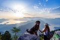 A sporty girl with a backpack stands on the edge of a mountain with a Rottweiler dog Royalty Free Stock Photo