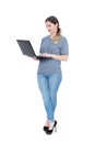 Young happy girl in casual clothes is standing with a laptop, isolated on white background