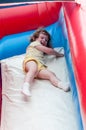 Young happy girl child riding inflatable slide outdoors on a warm summer day. Royalty Free Stock Photo