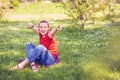 Young happy girl with earphones and smartphone listening to music on grass.