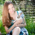 Young happy girl happy smiling & looking at camera embracing little rabbit outdoors Royalty Free Stock Photo