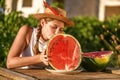 Young happy girl with hat and half of red fresh watermelon enjoying a outdoors. Teenager enjoying summer life Royalty Free Stock Photo