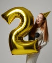 Young happy girl with huge gold digit balloon as a present for birthday party Royalty Free Stock Photo