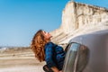 A young happy girl leans out of a car window on a trip to Crimea against a White rock background, concept of freedom Royalty Free Stock Photo