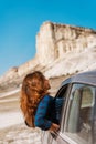A young happy girl leans out of a car window on a trip to Crimea against a White rock background, concept of freedom Royalty Free Stock Photo