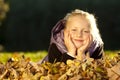 Young happy girl lying on floor in autumn leaves