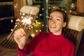 Young happy girl with sparkler in the evening on the terrace of the house. Holiday christmas and new year Royalty Free Stock Photo