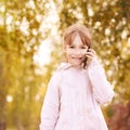 Young happy girl talks cellphone. Phone roaming. People with smartphone. Autumn background