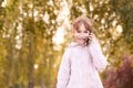 Young happy girl talks cellphone. Phone roaming. People with smartphone. Autumn background