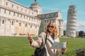 Young happy girl with toristic map on travel to Pisa. Tourist traveling visiting The Leaning Tower of Pisa. Royalty Free Stock Photo