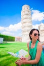 Young happy girl with toristic map on travel to Pisa. Tourist traveling visiting The Leaning Tower of Pisa. Royalty Free Stock Photo