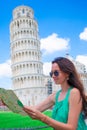 Young happy girl with toristic map on travel to Pisa. Tourist traveling visiting The Leaning Tower of Pisa. Royalty Free Stock Photo