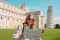 Young happy girl with toristic map on travel to Pisa. Tourist traveling visiting The Leaning Tower of Pisa. Royalty Free Stock Photo