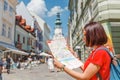 Happy girl traveler looks at the map and tries to find the right direction for the next attraction in the European city