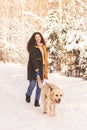 Young happy girl walks with dog labrodor in winter park Royalty Free Stock Photo