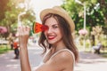 A young happy girl walks in the park with a lollipop in the form of watermelon