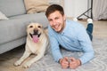 Young happy guy lying on floor with his dog