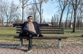 Young happy guy with sunglasses and smile sitting on the bench in the park enjoying the life and the sunny day Royalty Free Stock Photo